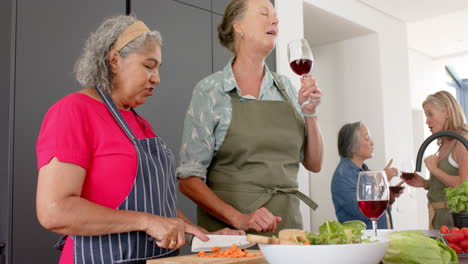 senior biracial woman and caucasian woman share a laugh while preparing a meal in a home kitchen