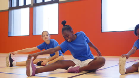stretching on gym floor, kids in school gym class wearing blue shirts