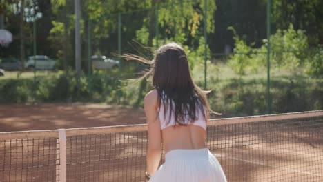 a young woman practicing tennis on an outdoor court with a coach. the coach provides guidance as the player works on her technique, perfecting her strokes in an athletic training session.