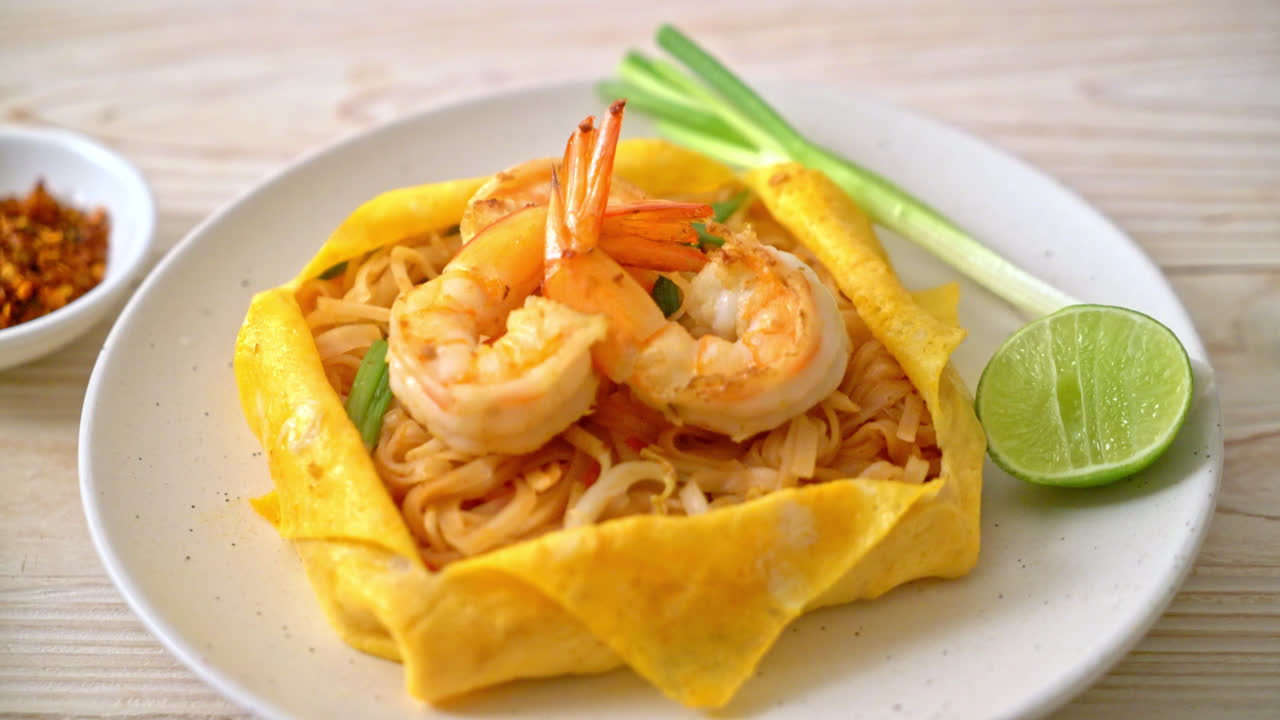 fideos fritos tailandeses con camarones y envoltura de huevo - estilo de comida tailandesa