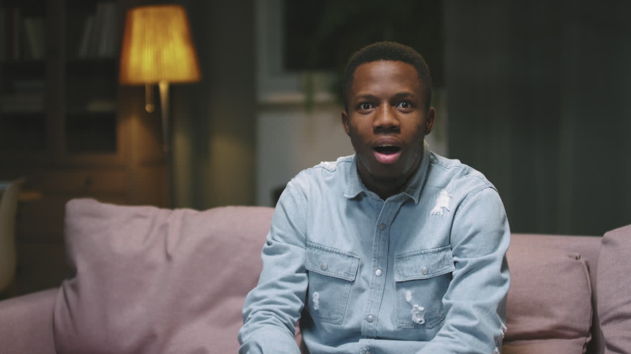 Uomo afro che guarda un film emozionante in TV