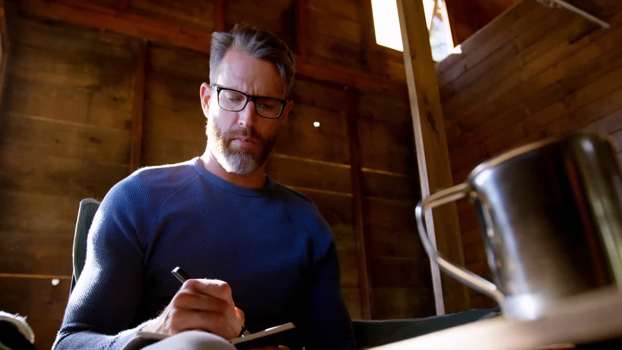 hombre escribiendo en un diario en casa 4k