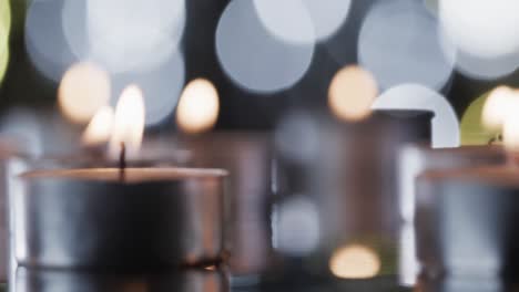 Video-of-tea-candles-with-white-flames-and-copy-space-with-bokeh-on-black-background