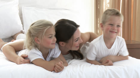 madre atractiva y niños jugando en la cama