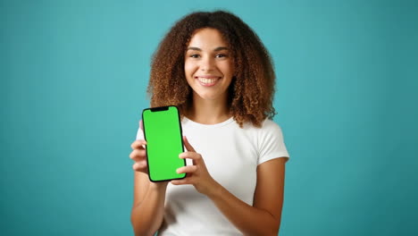 smiling woman holding a smartphone with a green screen