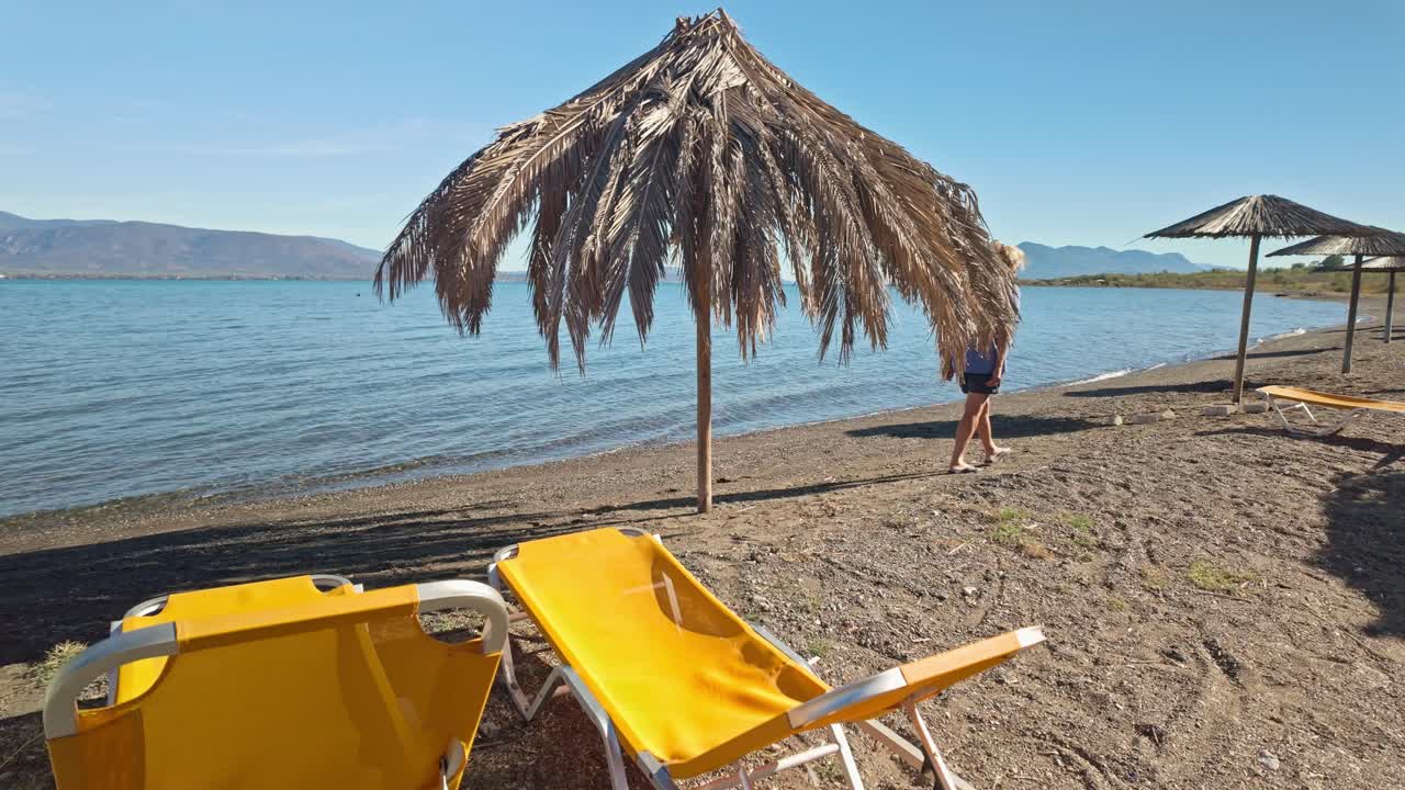 Woman walks alone on deserted off season Greek holiday seaside beach