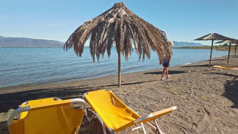 woman walks alone on deserted off season greek holiday seaside beach