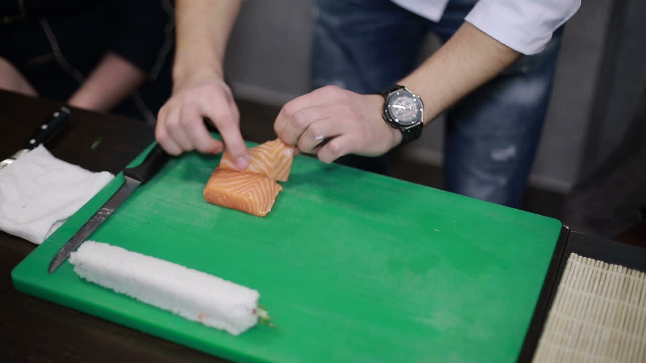 Making Salmon Sushi, Japanese Food. Chef is neatly cutting on fine part of salmon to make sushi