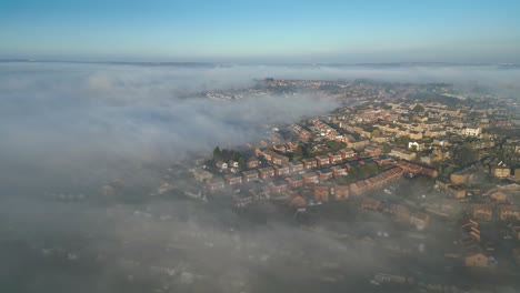 aerial drone point of view uk cityscape during sunrise, early morning landscape, residential building rooftops at dense fog, misty weather