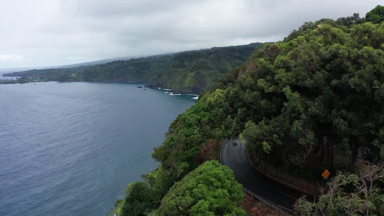 Low panning aerial shot of the tropical rainforest coastline along the Road to Hana on the island of Maui, Hawai'i