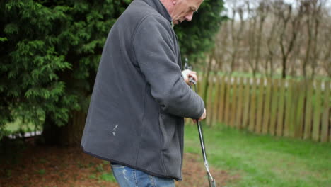 a mature bald man struggling to put tent poles at a campsite whilst camping