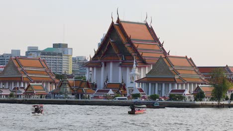 traditional temple by the water with passing boats