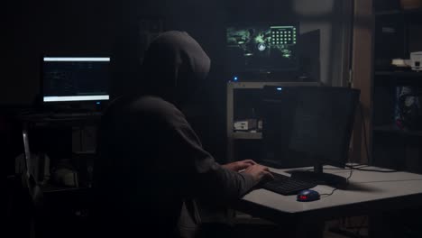 computer hacker types in computer code in a back room