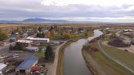 Drone-passing-beside-water-tower-of-quiet-town-and-river