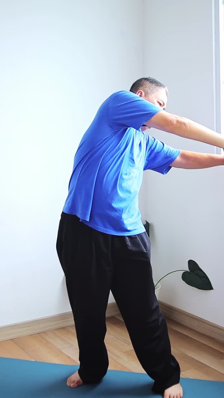 Homem asiático sênior alongando a parte superior do corpo antes de treinar no colchonete de yoga