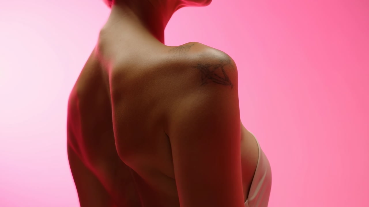 Woman Back Profile Against Pink Backdrop, Cinematic Studio Lighting Highlights Shoulder Tattoo And Skin