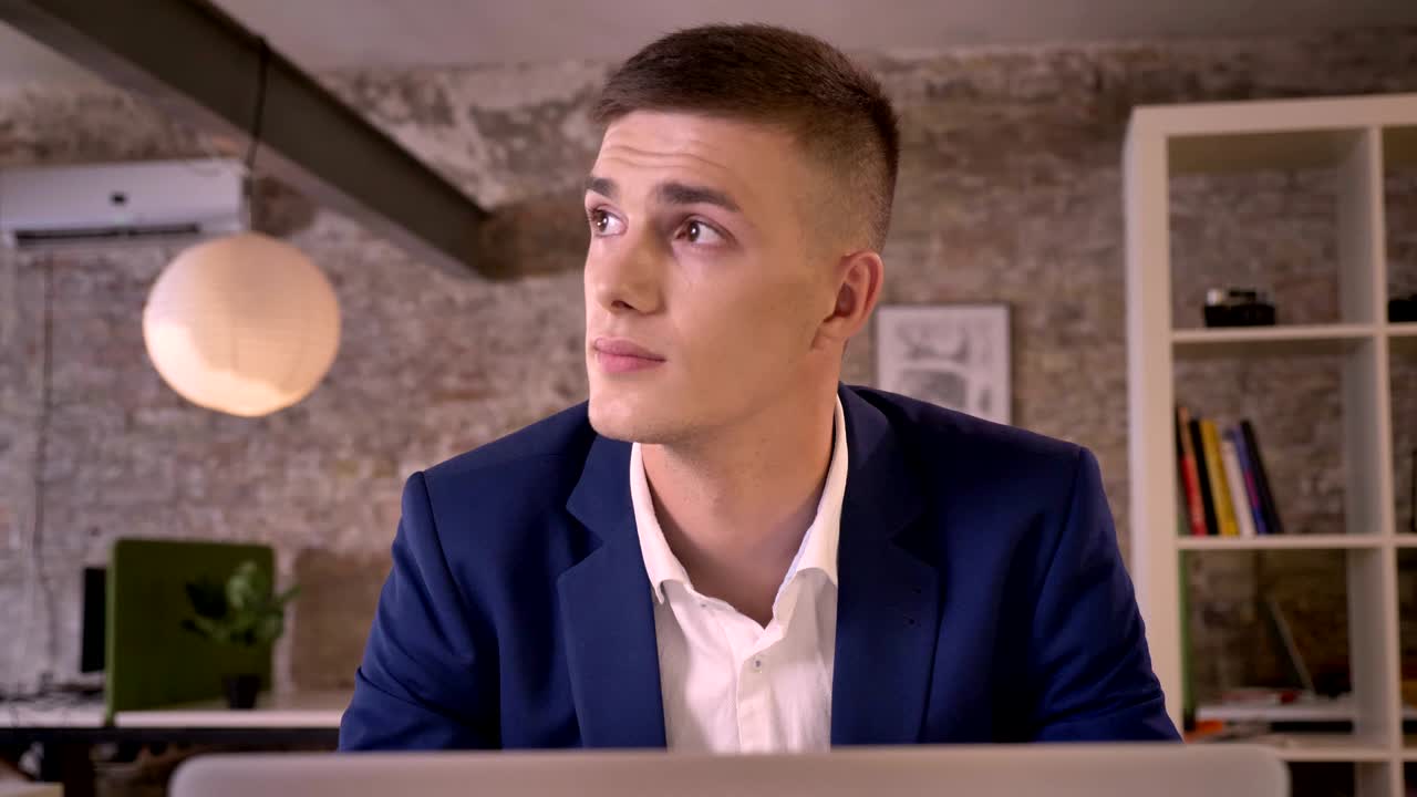 Young sweet businessman is working with laptop, watching in window, dreaming concept, communication concept, business concept