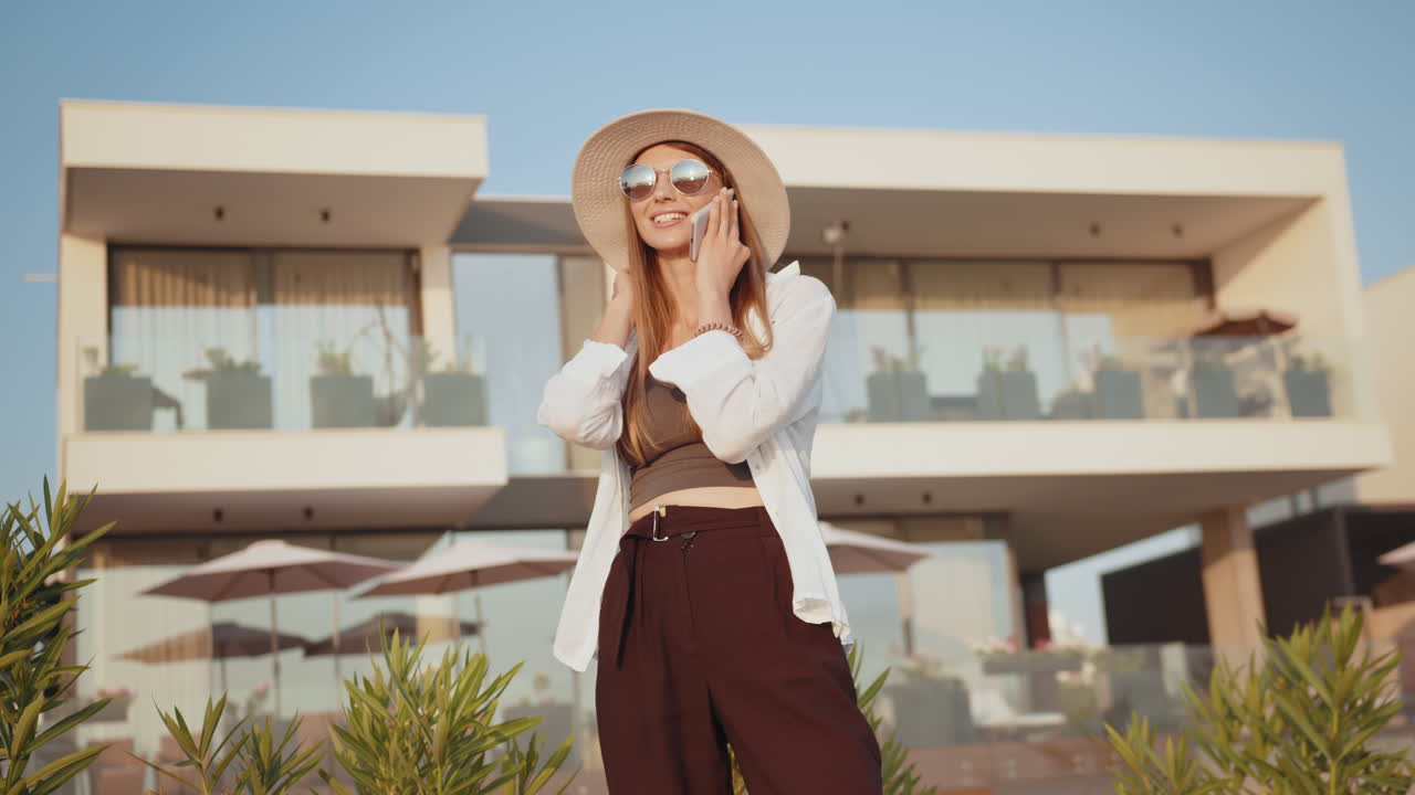 럭셔리 빌라 근처 에서 전화 를 사용하는 여자