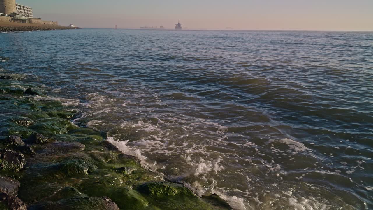 view from sunny seashore to the North sea ocean in Europe with water waves and sunlight with horizon