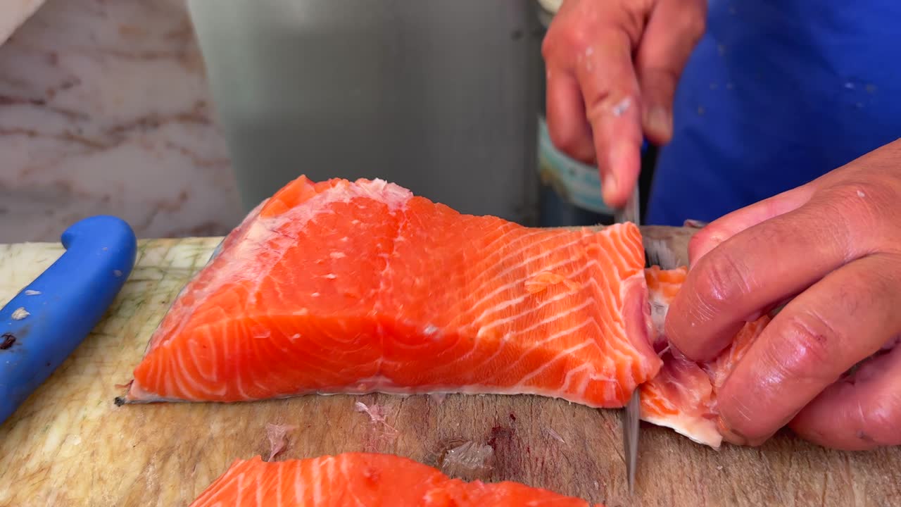 Close-up of hands filleting fresh salmon
