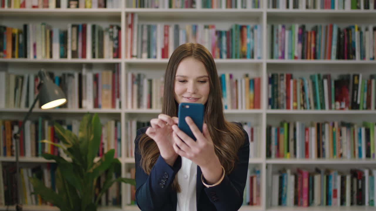 retrato de una mujer joven y hermosa de pie en la biblioteca estudiante usando un teléfono inteligente estudio de aprendizaje mensajes de texto en las redes sociales