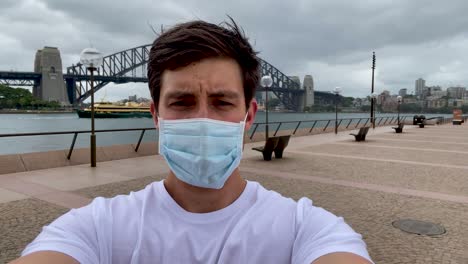 un modelo masculino toma una icónica selfie frente al puente del puerto de sídney sin las multitudes debido al brote de coronavirus en australia