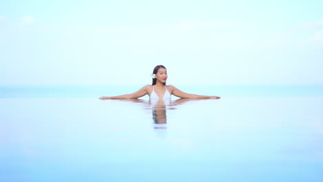 Misteriosa-Mujer-Asiática-Sexy-Dentro-De-La-Piscina-Infinita-Girando-Lentamente-Su-Vista-Hacia-La-Cámara-En-El-Simplista-Fondo-Del-Cielo,-Plantilla