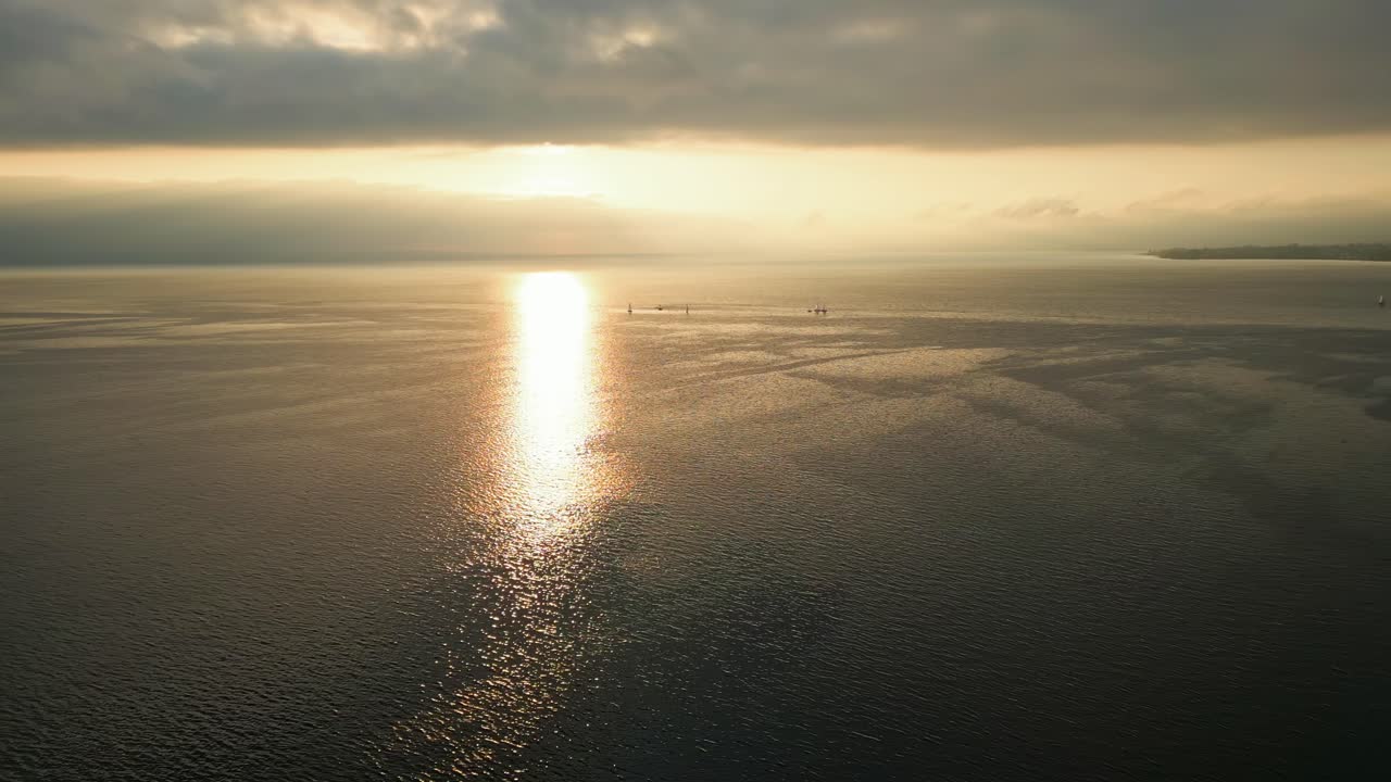 Pan drone shot of golden hour sunset over Lake Geneva with boat near Lausanne in Switzerland
