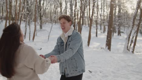 happy young beautiful couple have fun in sunny winter forest together