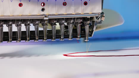 automatic embroidery machine is working. sewing machine needle in motion. sewing machine needles with different colors moves up and down on white fabric. close-up.