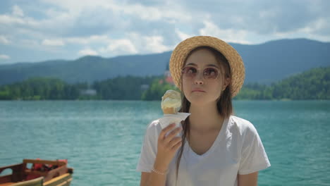 una mujer comiendo helado junto a un lago.