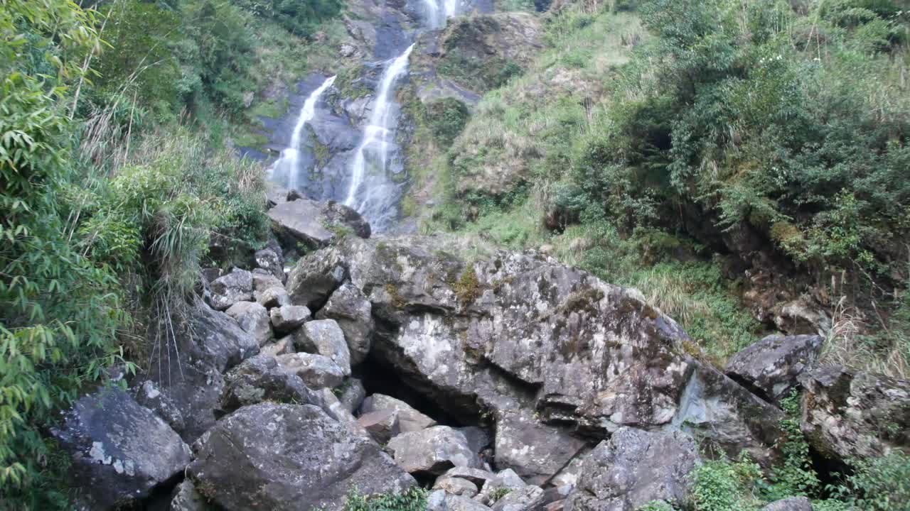 cascada en asia toma de seguimiento con un montón de plantas y rocas en primer plano