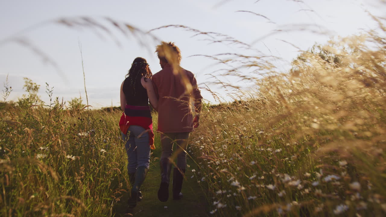 joven pareja romántica caminando por el campo hacia el teepee en vacaciones de campamento de verano