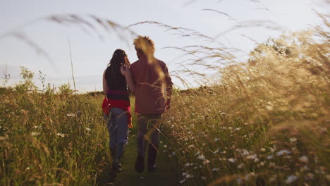 young romantic couple walking through field towards teepee on summer camping vacation