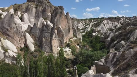 Approaching-drone-shot-flying-over-the-natural-rock-formations-and-ancient-cave-houses-of-Cappadocia,-in-Central-Anatolia-in-Turkey