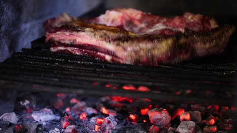 close-up of a man turning over an argentinian asado on a grill