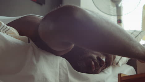 african american man turning off alarm clock after waking up