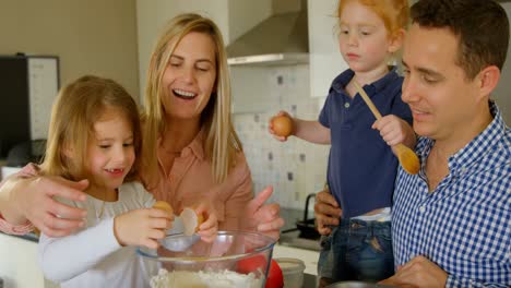 Parents-teaching-their-daughter-to-break-the-egg-while-baking-4k