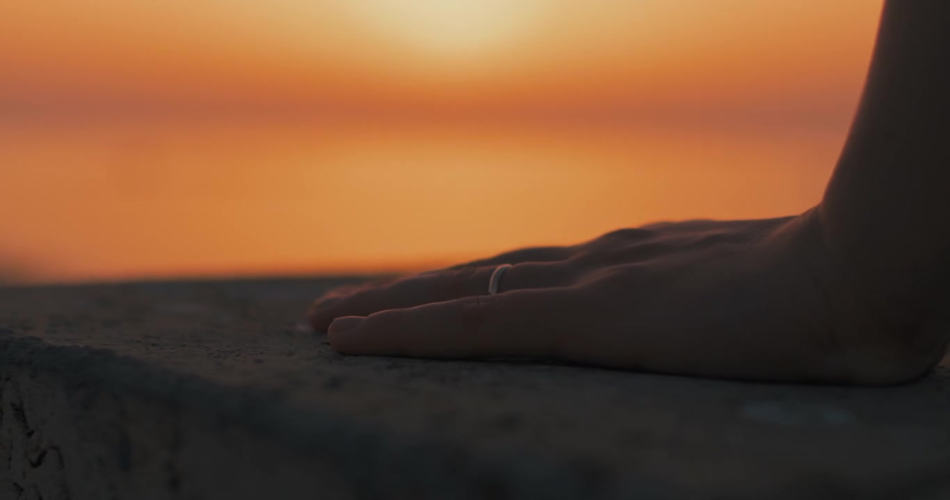 Mano con un anello d'oro al tramonto