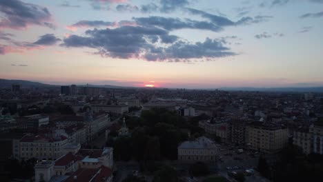 panning to reveal the red sun setting behind horizon in sofia, aerial
