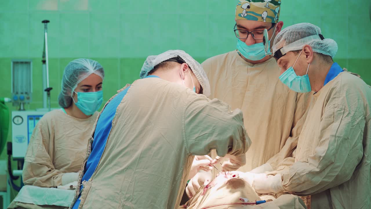 Chirurgo con la mascherina si concentra sull'intervento in ospedale, circondato dai colleghi. Concetto di chirurgia e emergenza. Primo piano