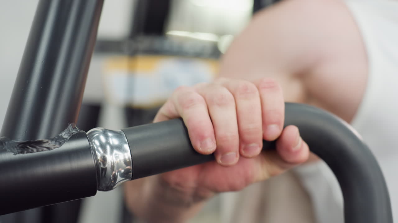 Man places hands firmly on handle of weight machine, initiating controlled movement as forearm muscles engage under gym lighting on sleek equipment for strength training session, showcasing power