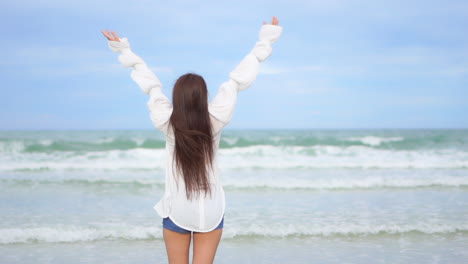 Feliz-Emocionada-Joven-Asiática-Corriendo-En-La-Playa-Y-Levantando-Las-Manos,-Cámara-Lenta-De-Fotograma-Completo