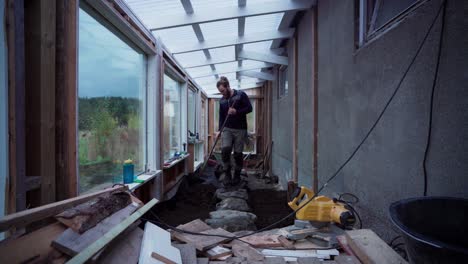 un hombre está distribuyendo cuidadosamente el suelo en el suelo para la construcción de un invernadero - toma estática