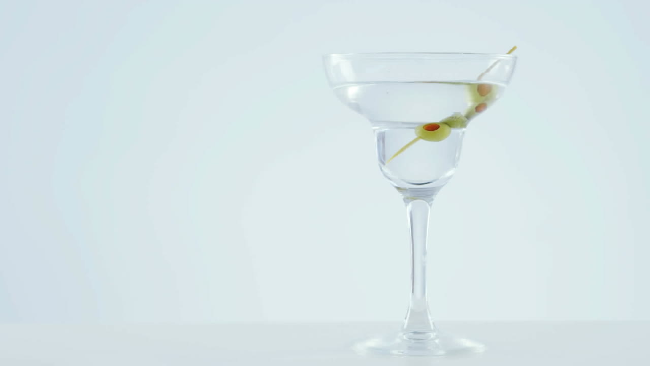Animazione di puntini rossi che si muovono su un bicchiere da cocktail con olive su sfondo bianco.