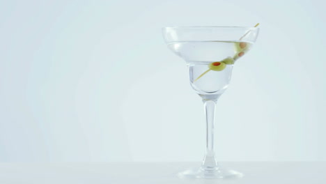 animation of red specks moving over cocktail glass with olives on white background