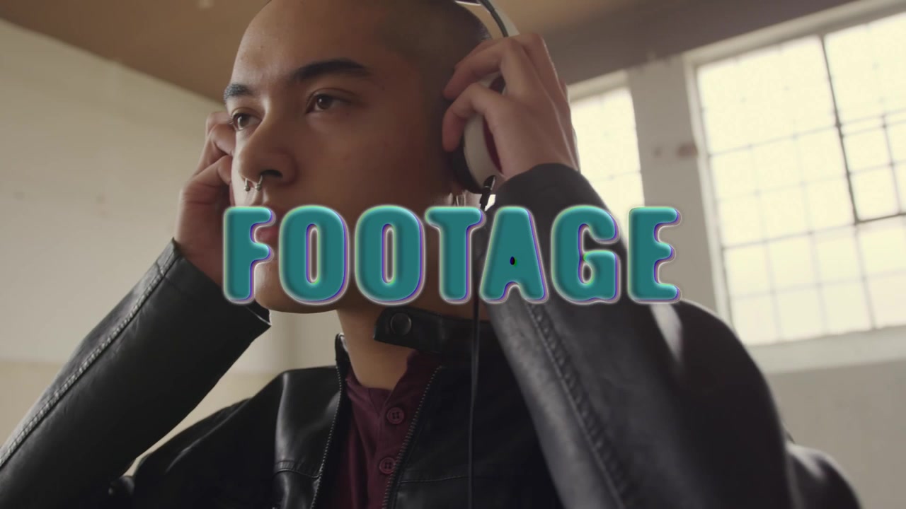 Young Man Wearing Headphones and Leather Jacket in Industrial Studio