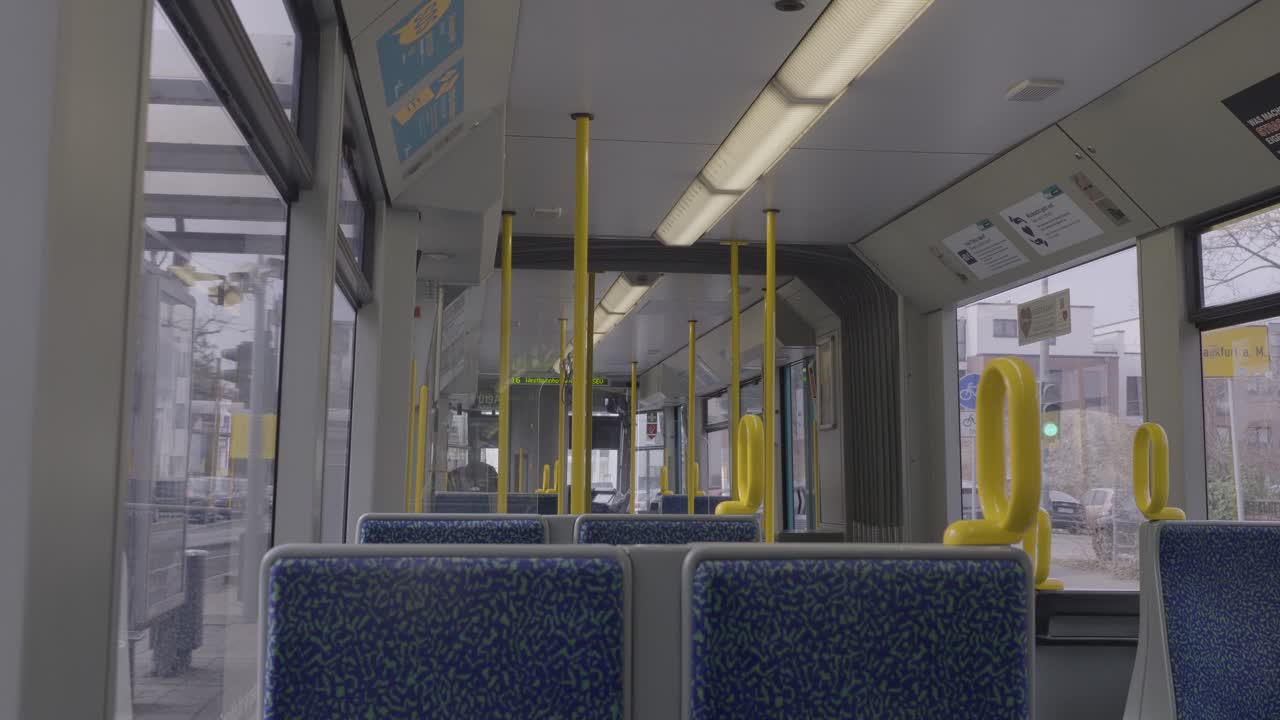 Interior view of a tram with empty seats and yellow poles, taken in Frankfurt