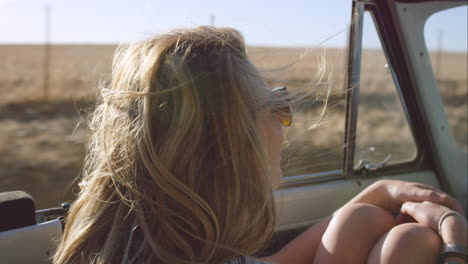 beautiful blonde friend enjoying road trip in vintage convertible car