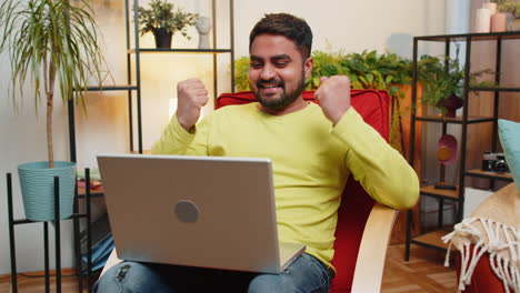 Amazed-Indian-man-use-laptop-computer,-receive-good-news-message-shocked-by-victory,-celebrate-win